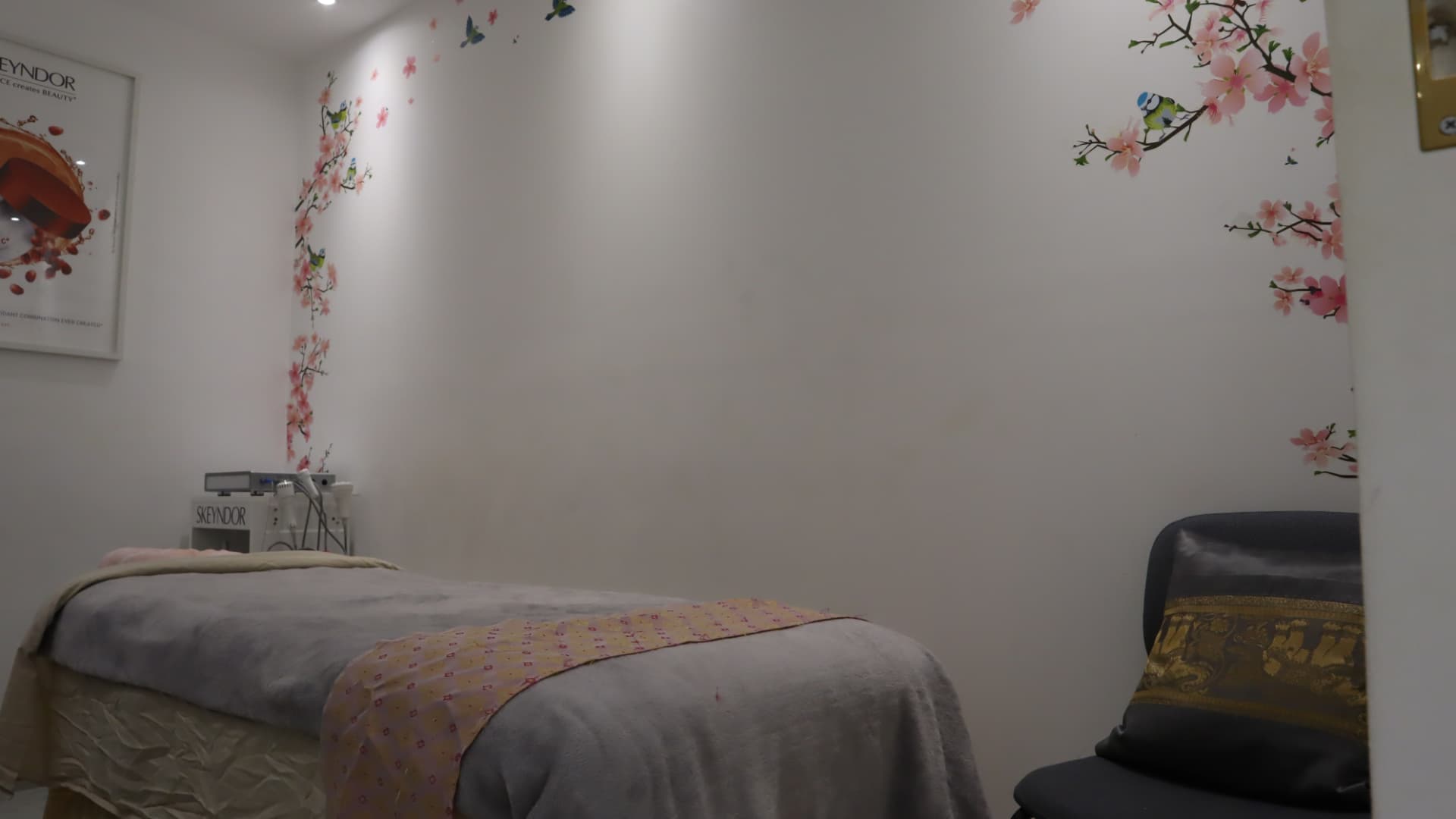 Facial room with a made-up treatment bed, Skeyndor equipment and cherry blossom wall art