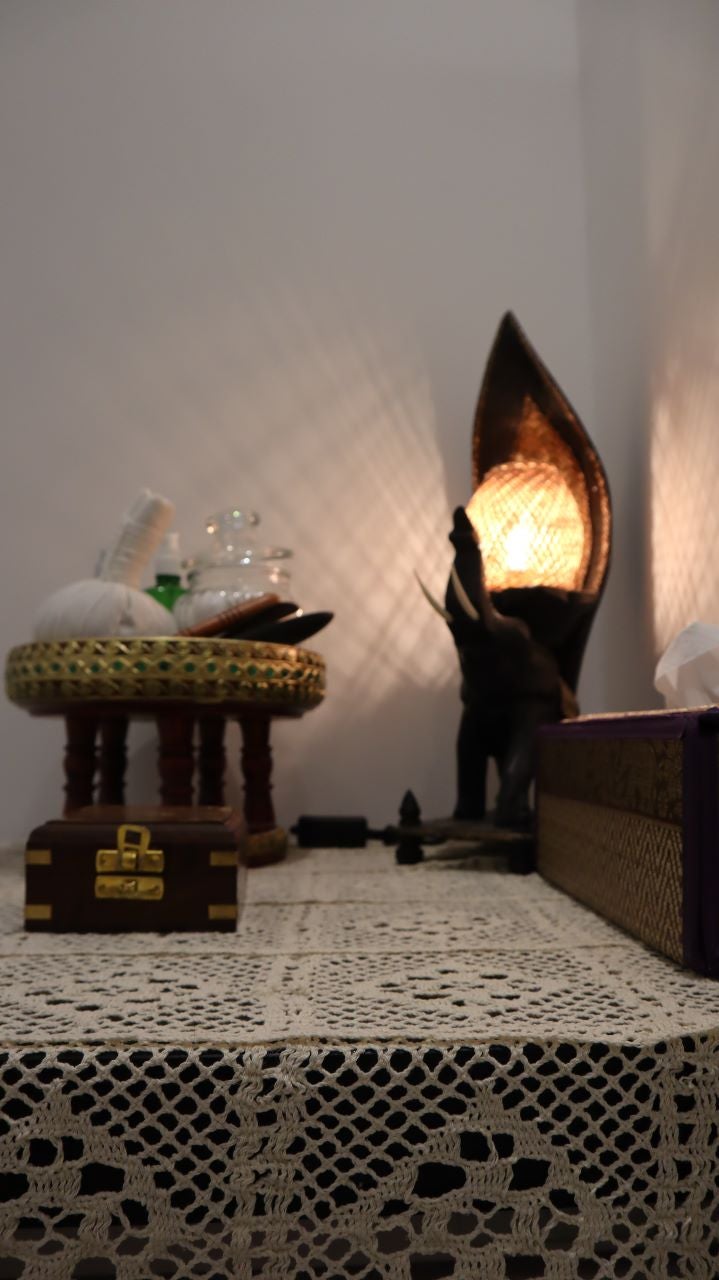 Treatment room lit by a single warm lamp beside a carved wooden screen